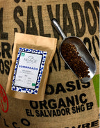 Sachet de café de spécialité bio Sombreado posé sur un sac de jute avec des grains de café – torréfaction artisanale à Hem, pour professionnels et particuliers, Nuage Coffee Roasters